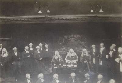 Image of Interior of Court Room with Three Seated Judges and Numerous Attendants