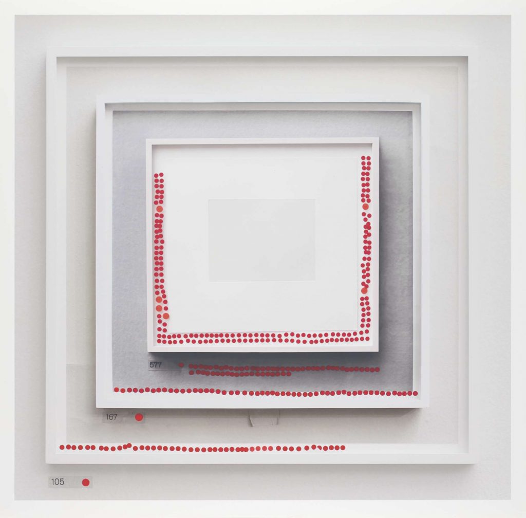 A framed photograph showing a framed photograph of a blank page within a framed photograph, within a framed photograph. Each frame has a series of red dot stickers around the edge.