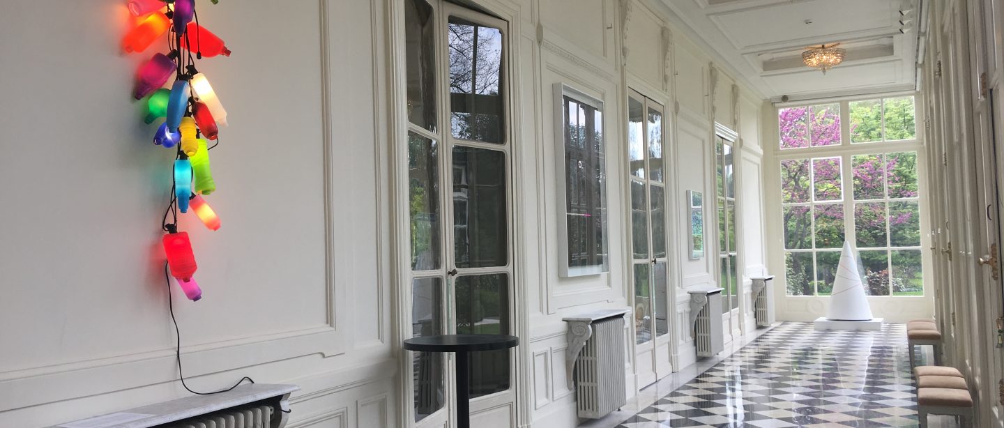 An airy and bright hallway overlooking the gardens, with a brightly coloured light work displayed on the left