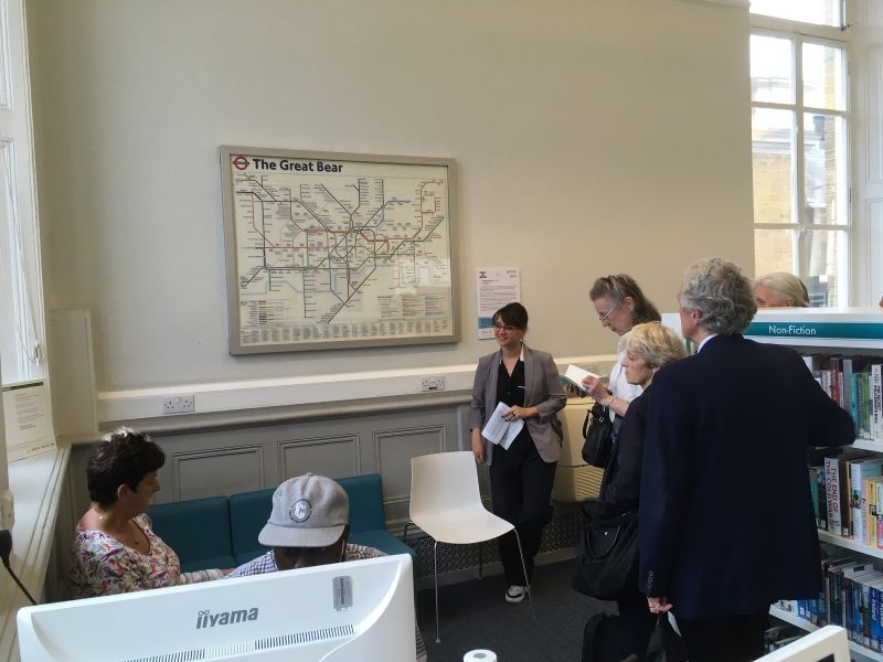 A group of people looking and talking in front of an artwork resembling the London Underground map