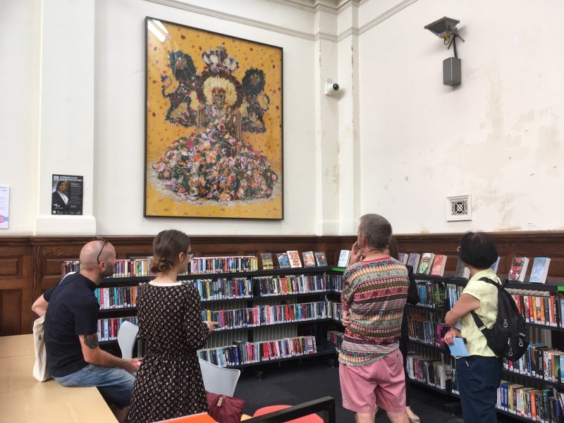 Four people looking at an artwork by Hew Locke on the wall of Walthamstow Library