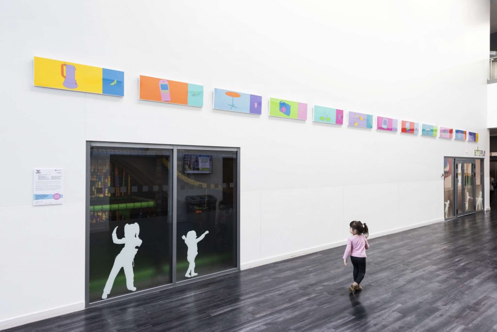 Small child walking in front of works of art