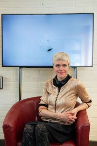 Melanie Manchot sitting in front of a large monitor