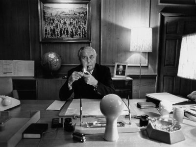 a man smoking a pipe at a desk in an office