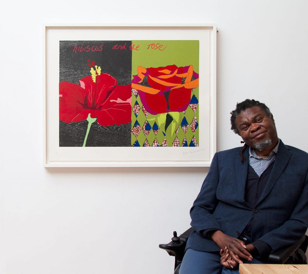 an artist sitting down with his work of art on the wall behind