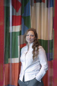 Elinor Morgan wearing a white shirt against a colourful background